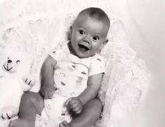 a baby sitting in a chair with a stuffed animal next to it's face