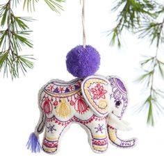 an elephant ornament hanging from a christmas tree with purple pom - poms