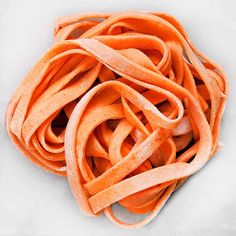 a pile of orange colored noodles on a white surface