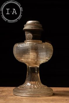 an old fashioned glass vase sitting on top of a wooden table next to a black background