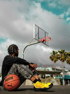 a man sitting on the ground with a basketball in front of him and a hoop