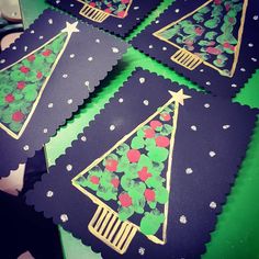 four christmas trees made out of paper sitting on top of a green table with snowflakes