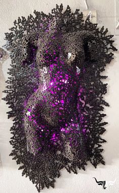 a purple and black sculpture is hanging on the wall