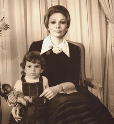 an old black and white photo of a woman sitting next to a child