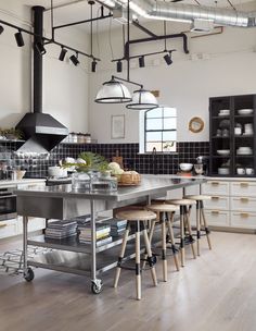 an industrial style kitchen with stainless steel counters and stools in the middle of the room