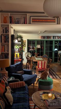 a living room filled with furniture and a cat sitting on top of the couches