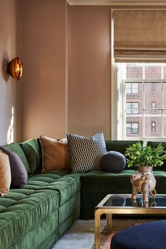 a living room filled with green couches and pillows on top of a coffee table