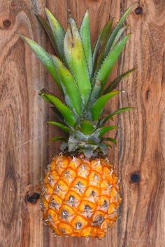 a pineapple on a wooden surface with green leaves