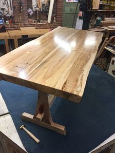 a large wooden table sitting on top of a blue mat in a room filled with tools