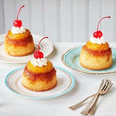 three small pastries with cherries on top and two forks next to them sitting on a table