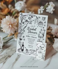 a white and black wedding card with flowers in the background on a marble countertop