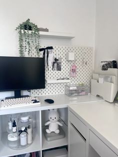 a white desk topped with a computer monitor next to a shelf filled with bottles and containers