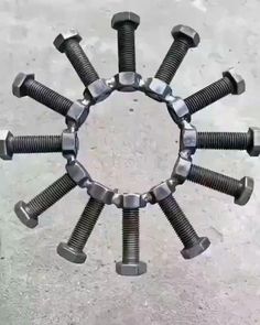 several bolts and nuts arranged in the shape of a circle on concrete flooring area