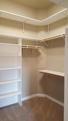 an empty walk in closet with white shelves