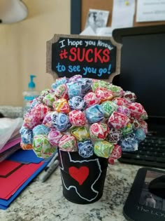 a cup filled with candy sitting on top of a table next to a laptop computer