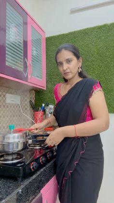 a woman in a sari is cooking on the stove