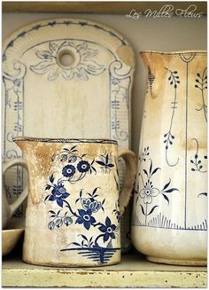 three vases are sitting on a shelf next to each other and one is painted with blue flowers