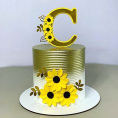 a cake decorated with yellow flowers and the letter c