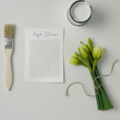 some flowers are sitting on a table next to a piece of paper and a brush