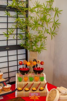 a table topped with lots of desserts next to a bamboo plant