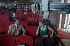 a man and woman sitting in red chairs