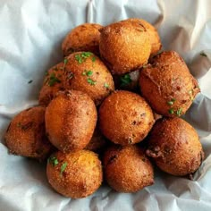 a pile of fried food sitting on top of a white table cloth covered in wax paper