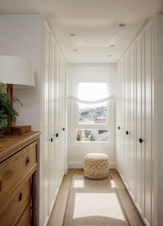 an empty hallway with white walls and drawers