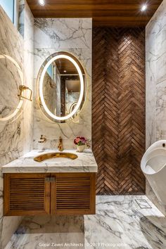 a bathroom with marble walls and flooring, round mirror on the wall above the sink