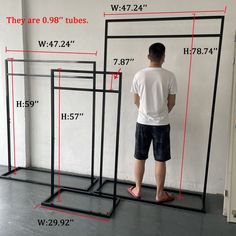 a man is standing in front of three tall black frames with measurements for each frame