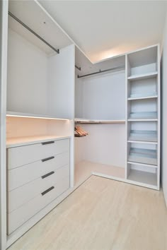 an empty walk in closet with white cabinets and drawers