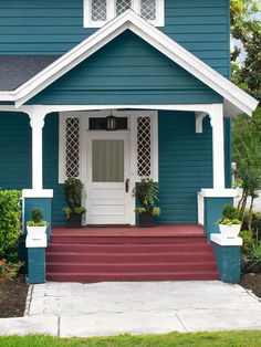 a blue house with red steps and white trim on the front door is seen in this image