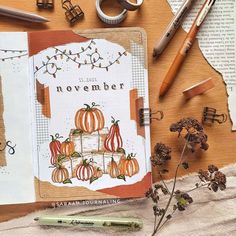 an open book with pumpkins and other items surrounding it on top of a table