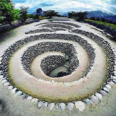 a spiral shaped rock garden in the middle of a field