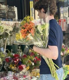 a man standing in front of a flower shop holding flowers