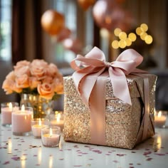 a present box sitting on top of a table next to candles and flowers in vases