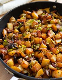 a skillet filled with cooked vegetables on top of a wooden table