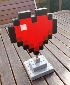 a heart made out of lego blocks sitting on top of a wooden table next to a bench