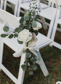 a bouquet of flowers sitting on top of a white wooden chair next to two rows of chairs