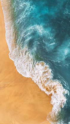 an aerial view of the ocean with waves coming in to shore and people walking on the beach