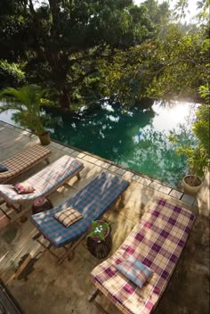 lounge chairs and blankets are on the deck overlooking a pool that is surrounded by trees