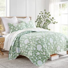 a bed with green and white comforters in a room