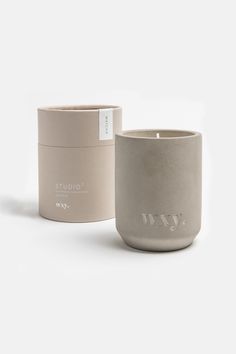 a candle that is next to a box on a white surface with the word w in it