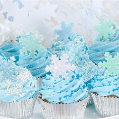 cupcakes with blue frosting and snowflakes on them sitting on a plate