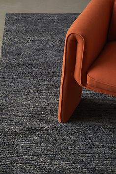 an orange chair sitting on top of a blue rug