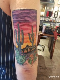 a woman's arm with a cactus and sunset tattoo on it