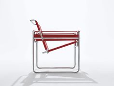 a red chair sitting on top of a white floor next to a metal frame structure