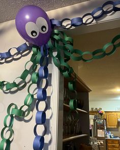 an octopus balloon is hanging from the ceiling in front of a door with green and blue streamers