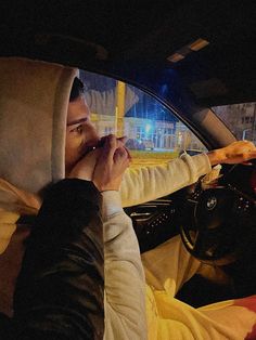 a man sitting in the driver's seat of a car talking on his cell phone