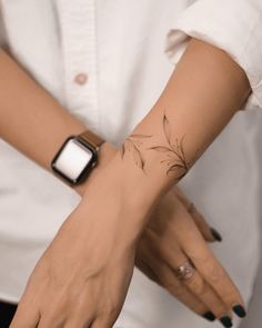 a woman's wrist with a small flower tattoo on her left arm and an apple watch in the other hand