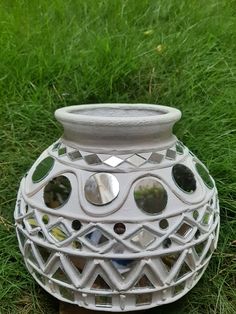 a white vase sitting on top of a lush green field